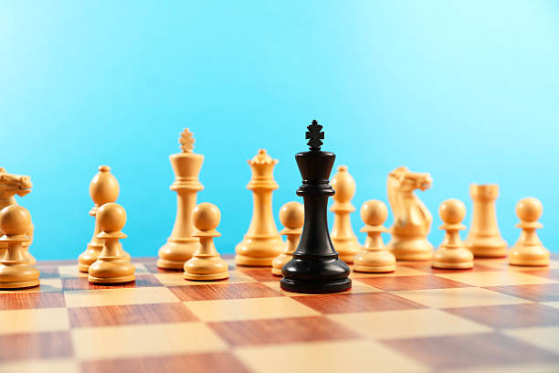 istock Black king in front of other white chess pieces on chessboard. Competition concept 2241592998