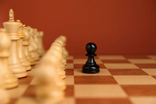 istock Black pawn in front of other white chess pieces on chessboard. Competition concept 2241593029