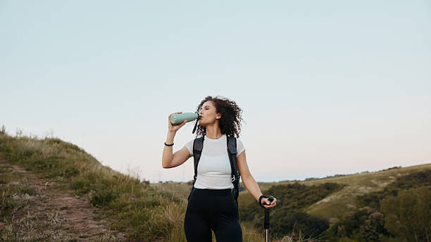 istock Woman hiker drinking water on a hillside trail 2241595345
