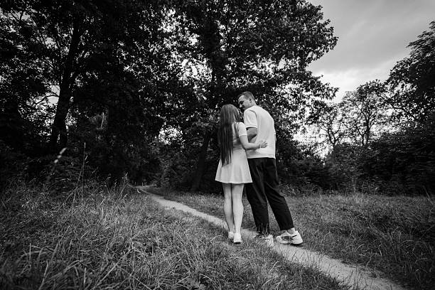 An elderly couple gently touching foreheads, eyes closed, soft smiles on their faces. The stark black and white contrast illuminates every wrinkle and gesture – a moment of deep affection and enduring intimacy.