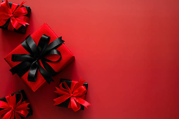 istock Black Friday background with a striking red gift with black ribbon and three small black gifts on a red background 2241598735