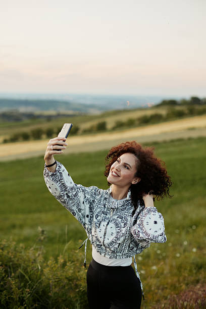 istock Woman taking a selfie on hillside with red backpack 2241600044