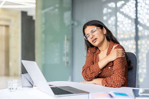 istock Stressed woman feeling shoulder pain at office desk 2241603194