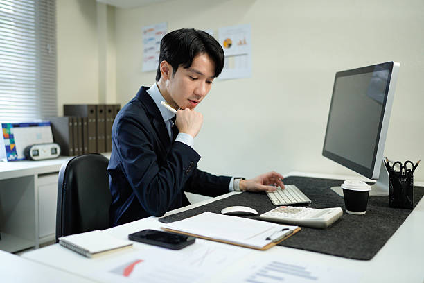 istock Business man, thinking and computer at desk in office for online research, reading email or report. Male entrepreneur person with internet connection for feedback, review and focus on project 2241604852