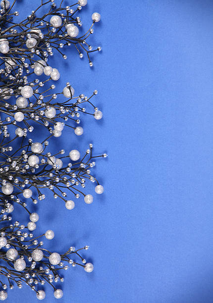 Christmas decoration with artificial berry twigs made of glittering beads, photographed on a blue background.