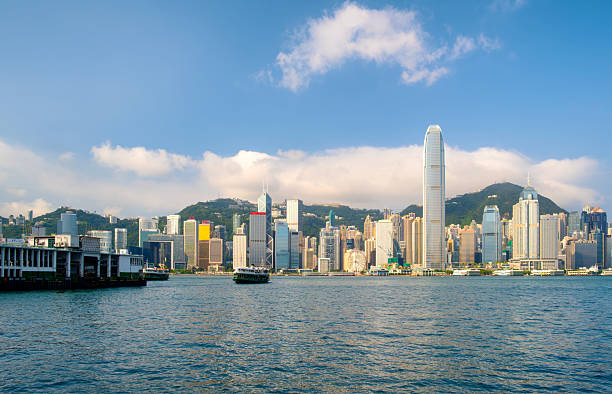 One of Hong Kong's iconic Star Ferries approaches the ferry terminal at Tsim Sha Tsui. The modern skyscrapers of Hong Kong Island can be seen in the background.