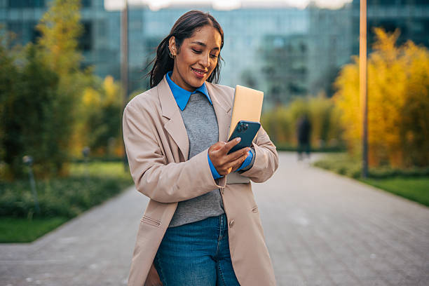 istock Professional woman walking and using smartphone with laptop 2241610221