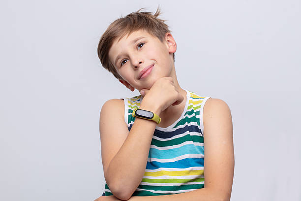 Young boy with striped shirt poses thoughtfully, showcasing a playful expression in a simple setting