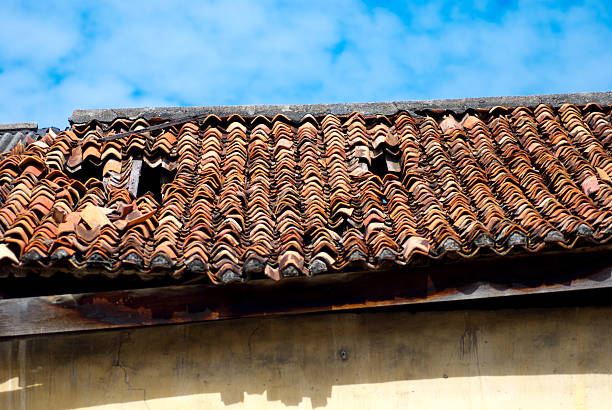 istock Old clay tile roof with several broken and misaligned tiles 2241618035