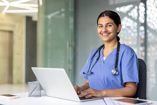 istock Smiling nurse working on laptop in modern hospital setting 2241619826