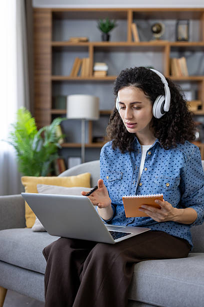 istock Woman e-learning at home using laptop and headphones 2241623211