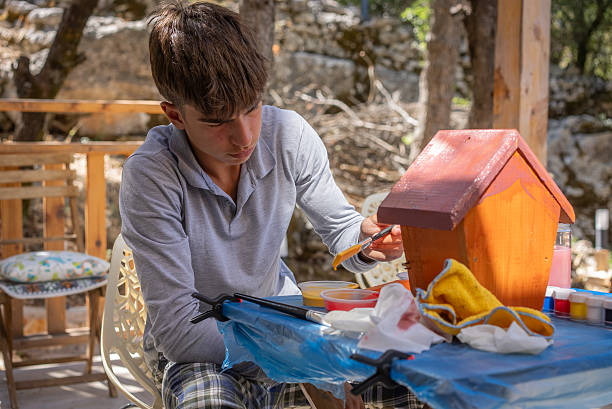 Young boy Having Fun Painting Bird Houses Outdoor in backyard.