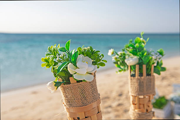 Closeup detail of flower plant bouquet decorations in holders wedding decoration with tropical blue ocean in background