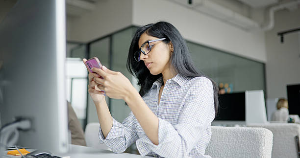 istock A focused woman uses a pink smartphone at a modern office desk 2241626155