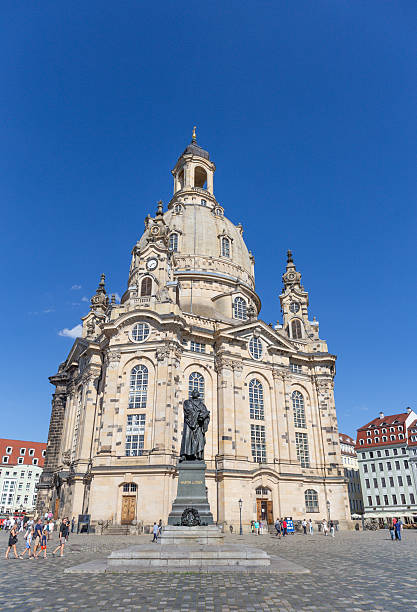 Dresden,Saxony,Germany-December 19 2014:a street scene in the historic city center Neumarkt square known for its baroque architecture. a moment of daily life with people walking on the wet, cobbled street under umbrellas on an overcast day.