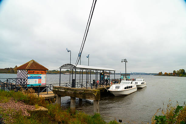 Shlisselburg, Russia - May 13, 2024: The ferry pier on the mainland shore of the Neva River with two small passenger boats docked, providing transport to Oreshek Fortress