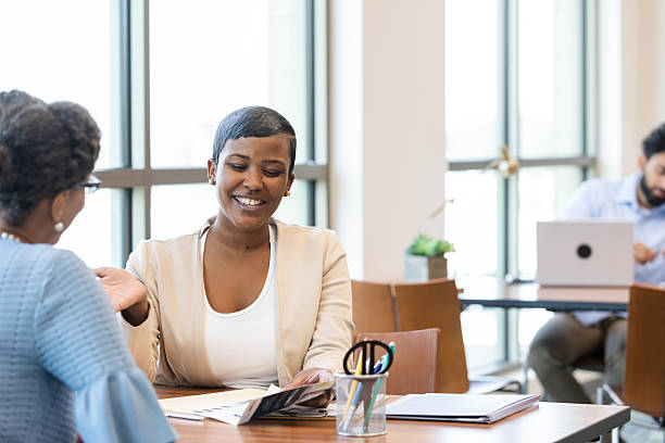 istock Two women having a cheerful conversation, reviewing documents at a table 2241629890