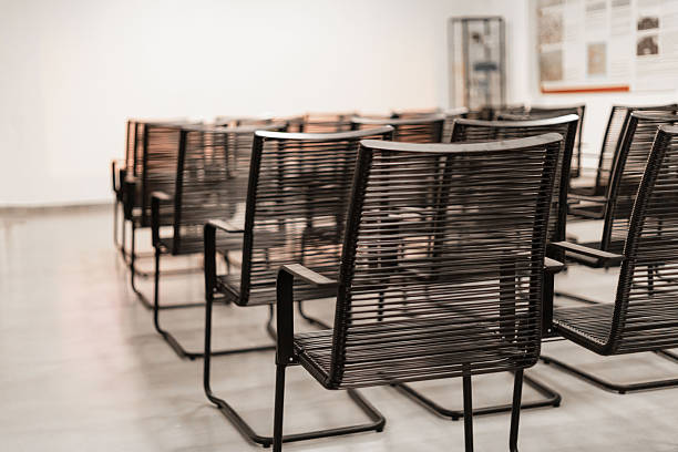 Several sleek black chairs are neatly arranged in rows within a bright gallery space. The walls feature informational displays, creating a welcoming atmosphere for visitors.