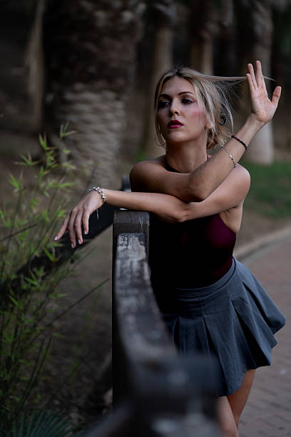 Woman standing outdoors, posing gracefully with hands on wooden railing, enjoying a moment of reflection in nature