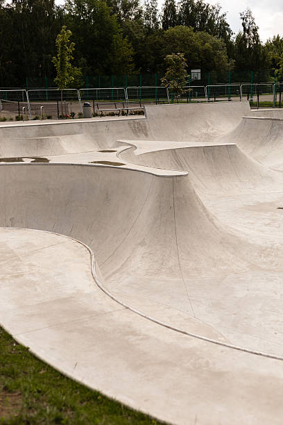 istock A modern skatepark features smooth, flowing concrete structures with various ramps and bowls, ideal for skateboarding and BMX activities. The park is surrounded by green trees and is well-maintained 2241636528