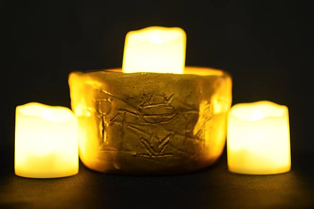 Ceramic mug with images of rock paintings surrounded by candles on a black background.