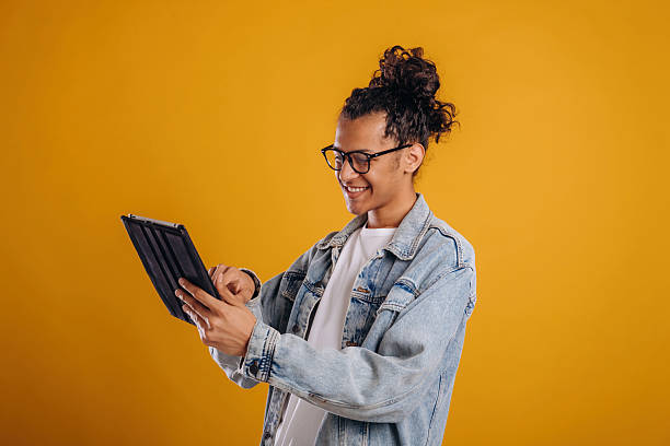 istock Digital tablet is in hands. Young guy is against yellow background 2241638953