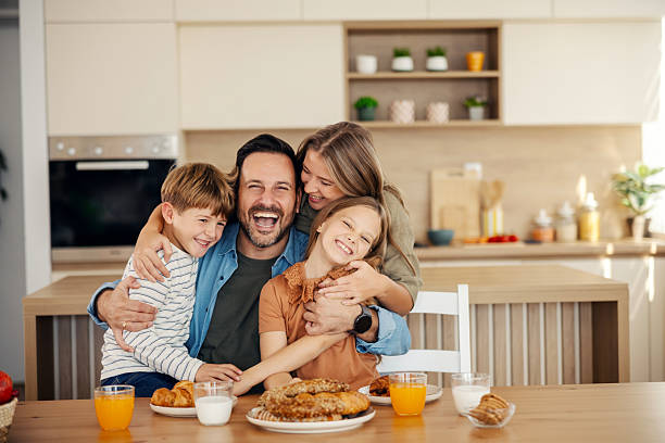 istock Family laughing and hugging during breakfast in kitchen 2241641419