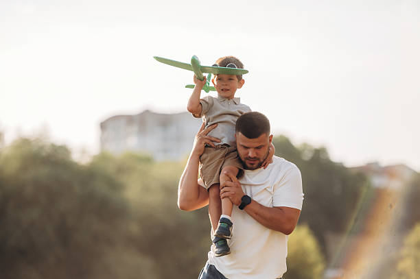 istock Toy plane in hand. Dad is holding son, having fun on the field 2241644546