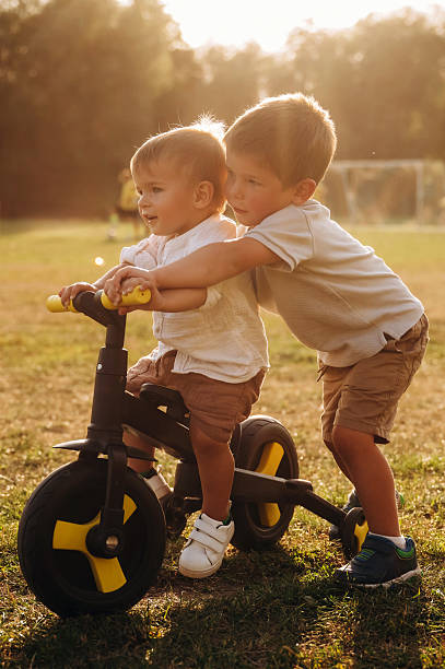 Learning to ride. Kids are playing with bicycle on the field.