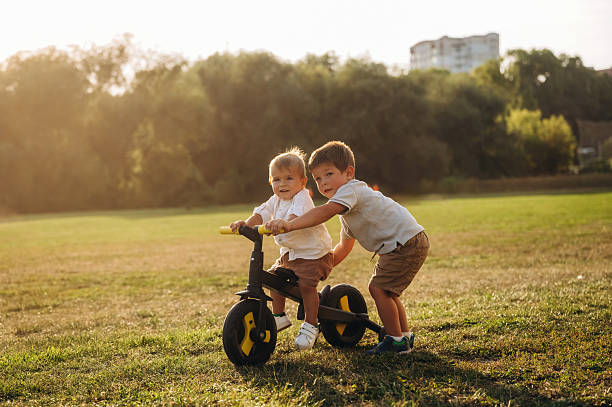 istock Learning to ride. Kids are playing with bicycle on the field 2241644896