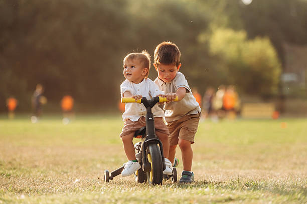 Learning to ride. Kids are playing with bicycle on the field.