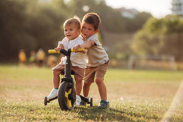 istock Learning to ride. Kids are playing with bicycle on the field 2241645950