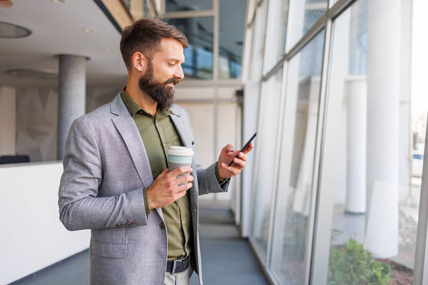 istock Businessman using phone and drinking coffee in modern office 2241646905