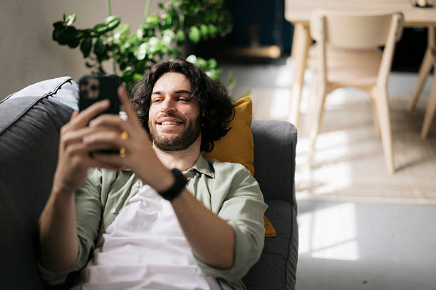 istock Happy man lying on sofa and using mobile phone at home 2241647202