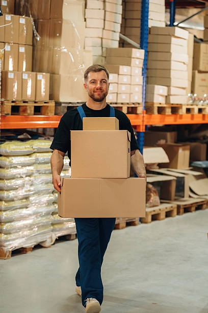 istock Man in uniform is working in the storage with packages for shipment 2241647873