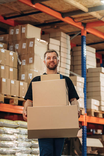 istock Man in uniform is working in the storage with packages for shipment 2241648629