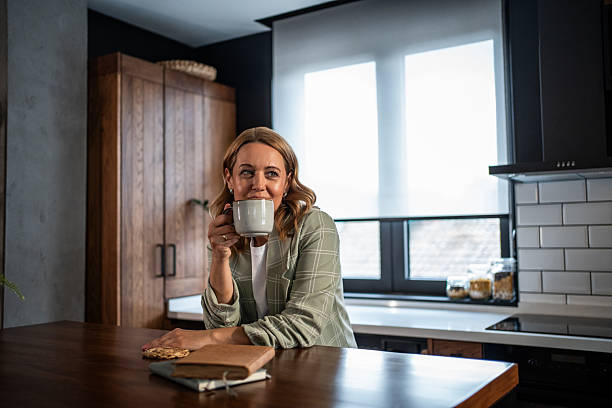istock Woman drinking coffee in kitchen taking a thoughtful break 2241649874