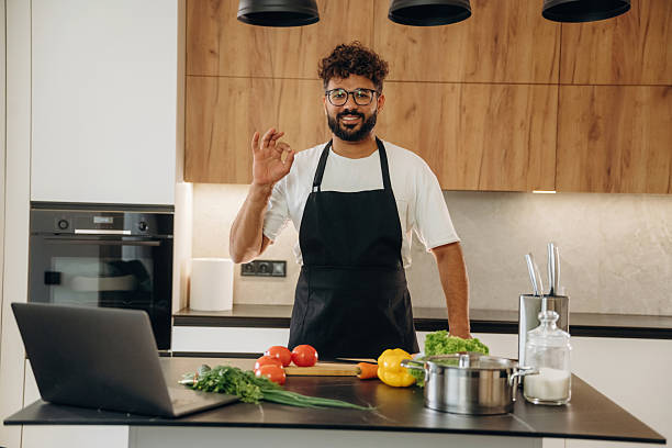 istock Standing and smiling. Handsome man is preparing food on the kitchen 2241650285