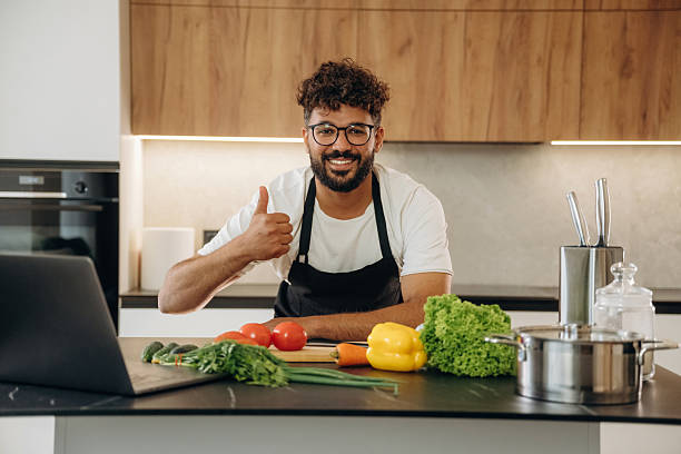 istock Standing and smiling. Handsome man is preparing food on the kitchen 2241650307