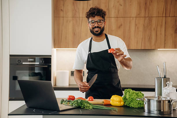 istock Slicing the vegetables. Handsome man is preparing food on the kitchen 2241650352