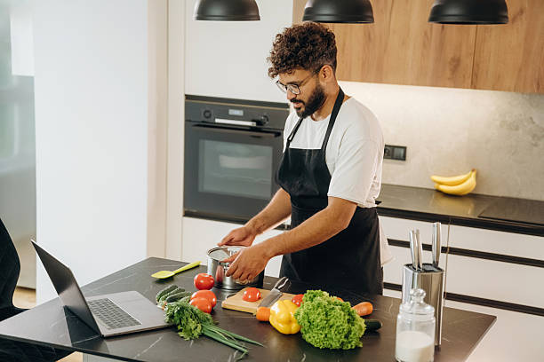 istock In black apron. Handsome man is preparing food on the kitchen 2241650378