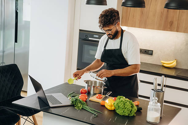istock In black apron. Handsome man is preparing food on the kitchen 2241650382