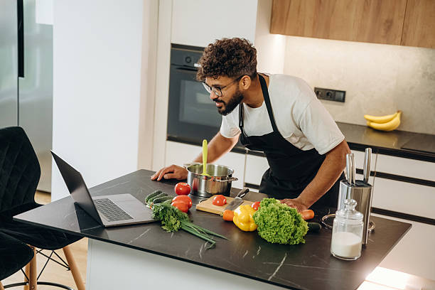 istock In black apron. Handsome man is preparing food on the kitchen 2241650388