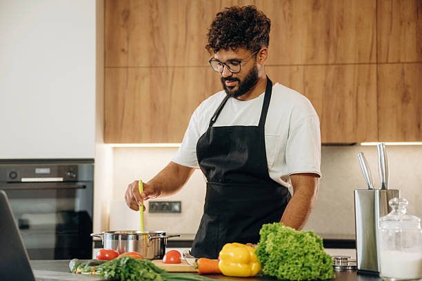 istock Fresh vegetables, making salad. Handsome man is preparing food on the kitchen 2241650402