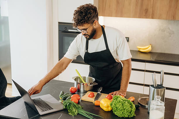 istock Fresh vegetables, making salad. Handsome man is preparing food on the kitchen 2241650411