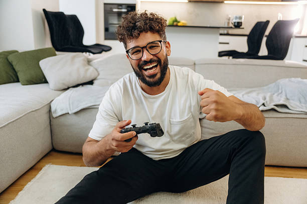 istock Celebrating victory, playing video game by using controller. Man is in the modern domestic room at home 2241651043