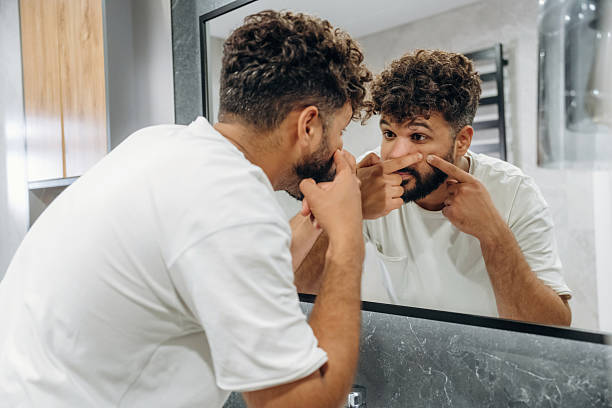 istock Squeezes pimples, pop it. Guy is in the bathroom, taking care of his appearance 2241651147