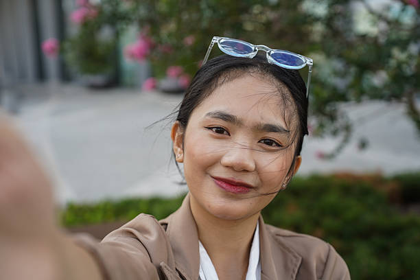 istock Young woman taking selfies and having a video call outdoors in a modern urban setting 2241656720