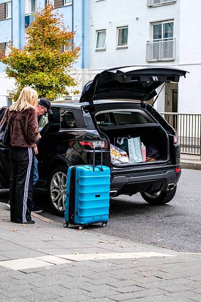 Epsom, London UK, October 17 2025, Middle Aged Man And Woman Couple Loading Car With Blue Suitcase