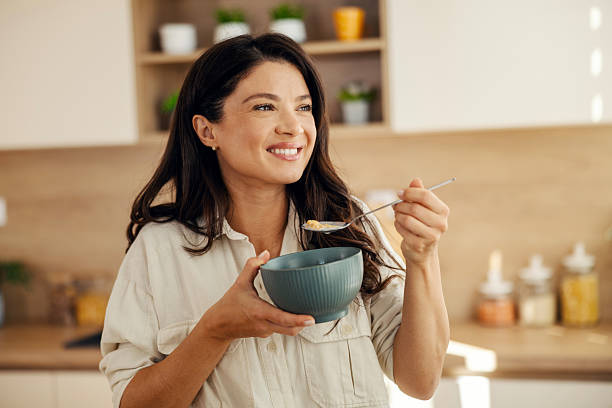 istock Happy woman enjoying healthy breakfast cereal in kitchen 2241659542